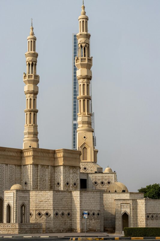 Imposing mosque with twin minarets in Ajman, UAE, showcasing traditional Islamic architecture.
