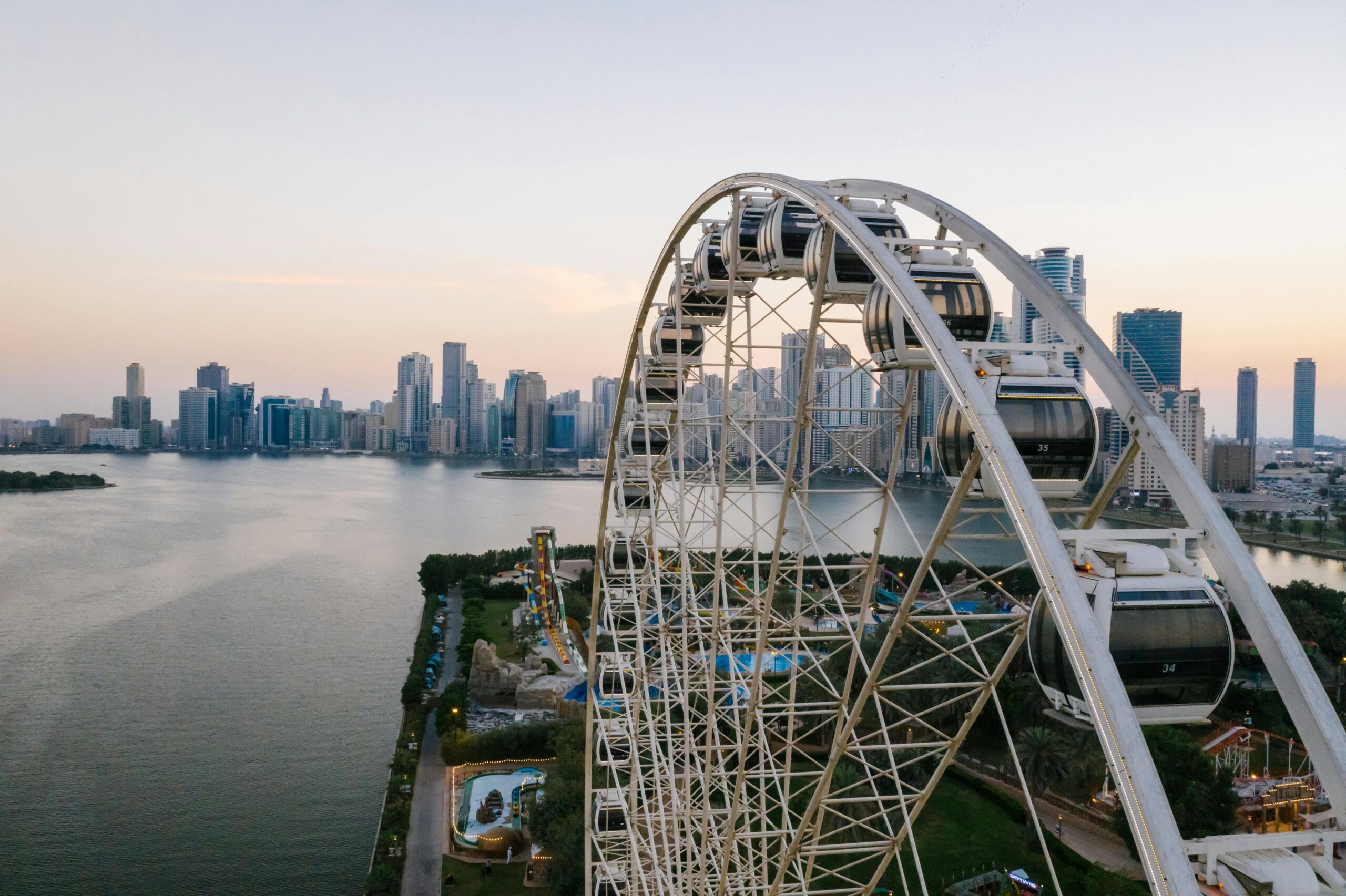 Ferris wheel overlooking a vibrant city skyline at sunset, perfect for travel inspiration.